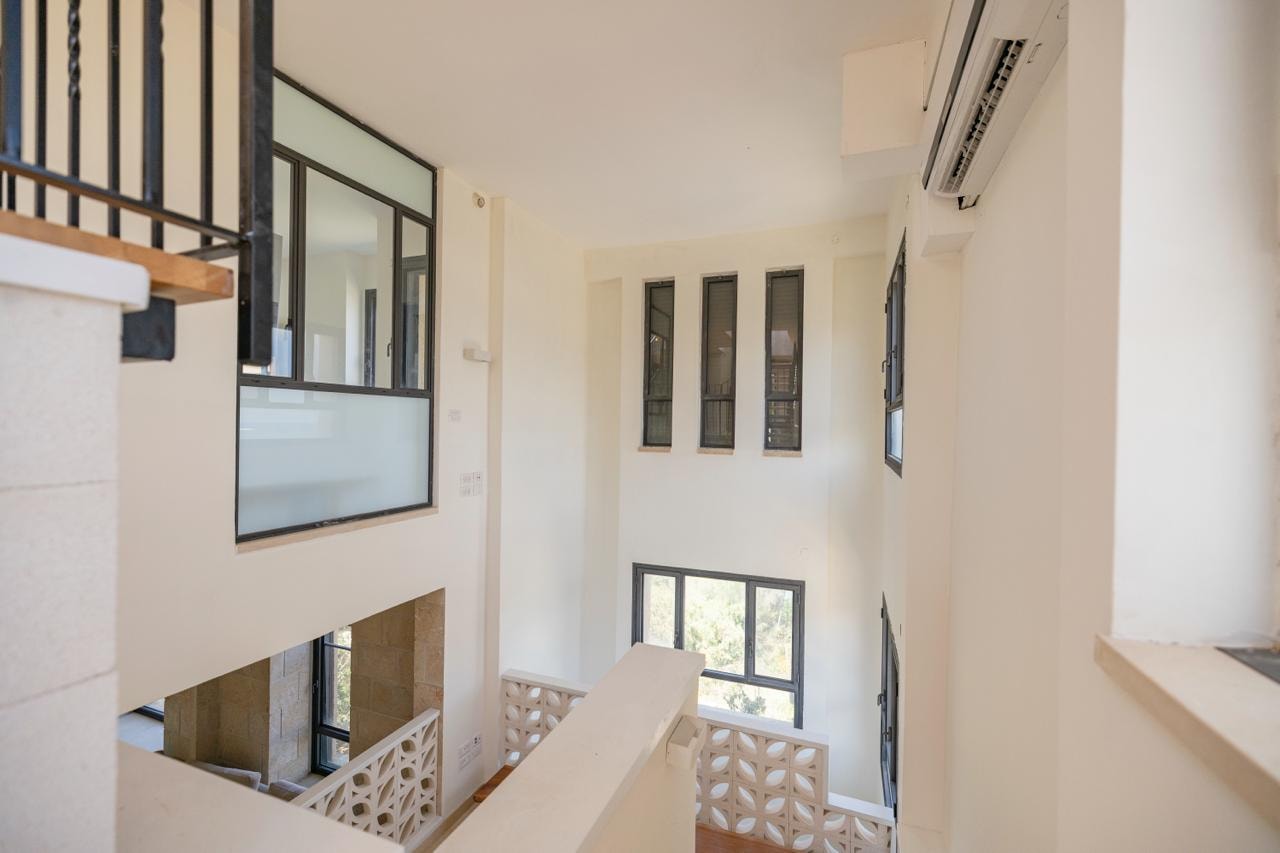 Double-height interior stairwell with stone walls and steel-framed glazing